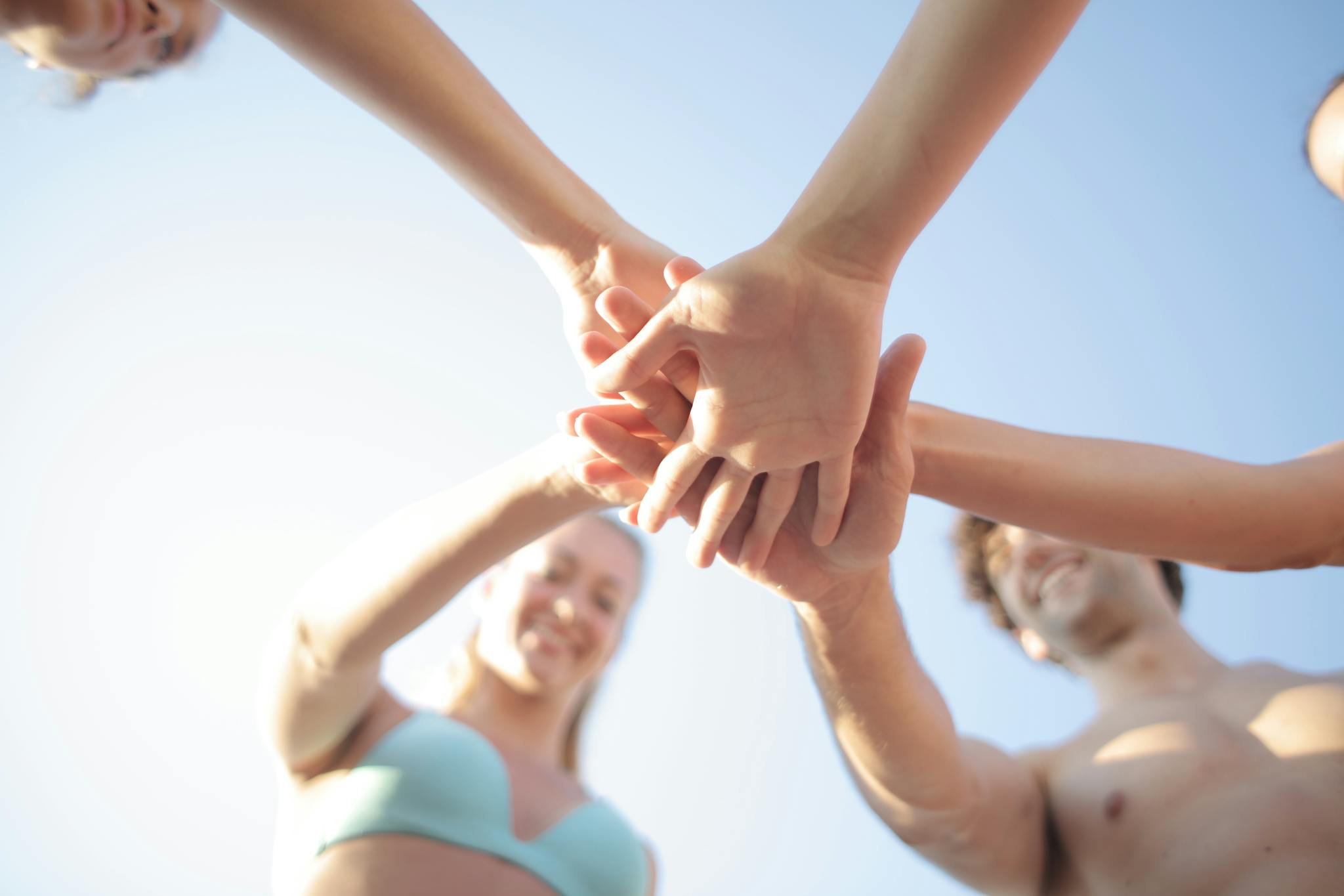 A group of diverse friends joining hands under the summer sun, symbolizing unity and friendship.