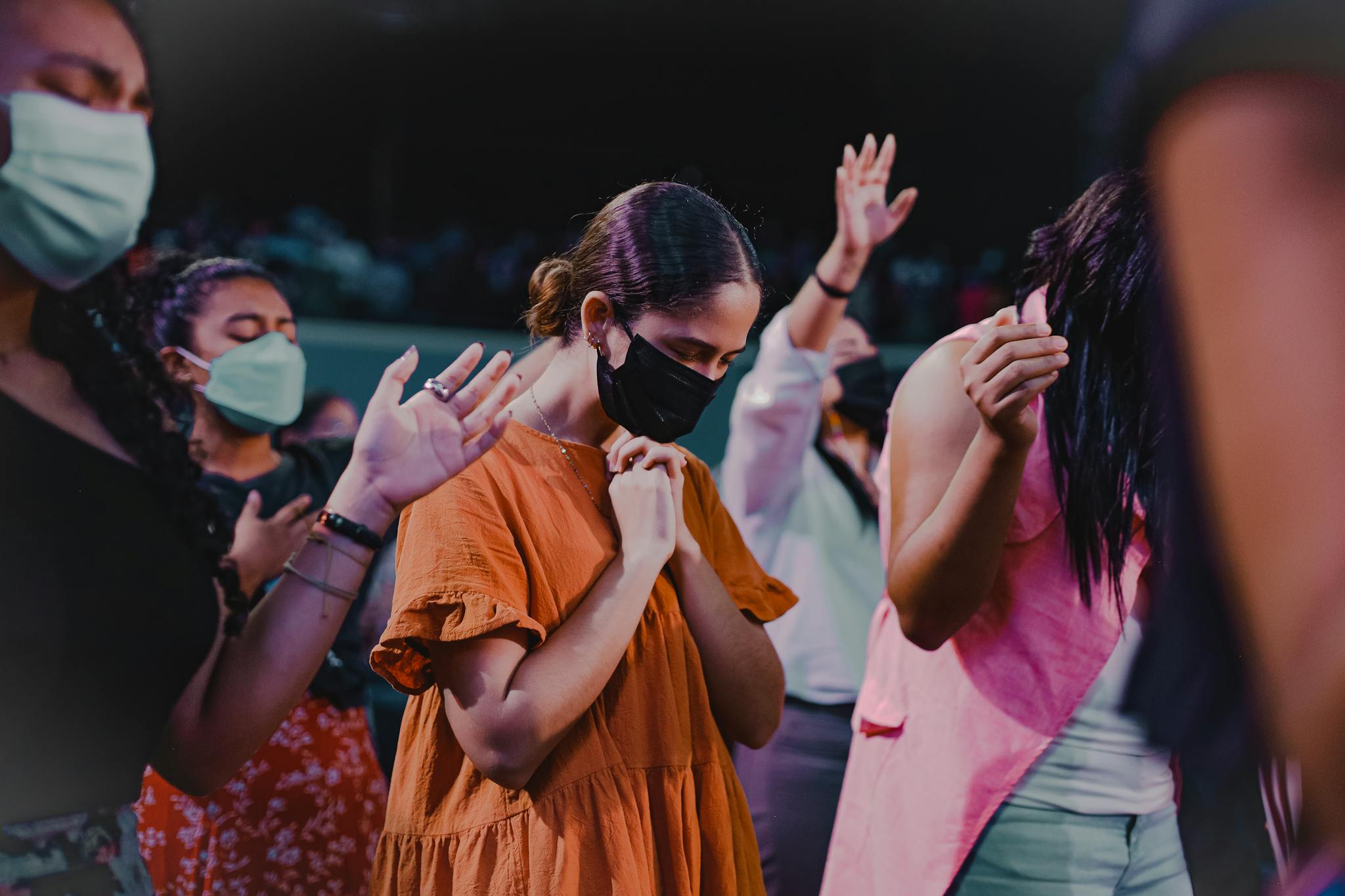 A group of people worshipping indoors, wearing masks, reflecting new normal practices.